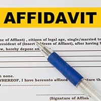 A closeup of the word Affidavit in capital letters at the top of a form with a pen lying across the form