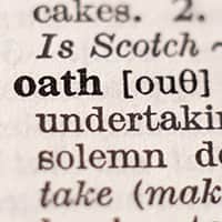 A closeup of the word oath in a dictionary with parts of the definition surrouding